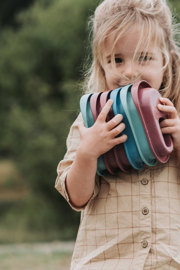 young girl playing with boat toys outdoors