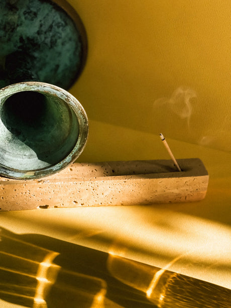 Incense stick burning in a wooden holder with a yellow background