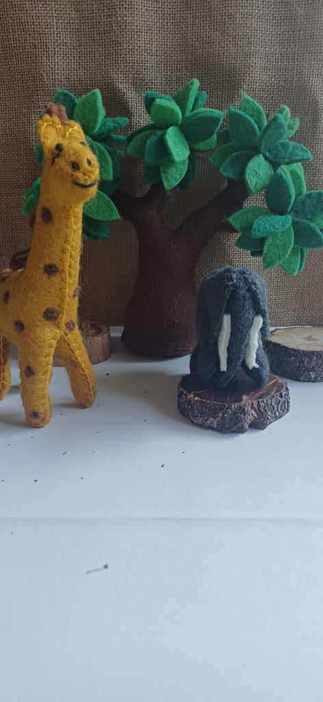 Toy giraffe and elephant with a tree on a white surface