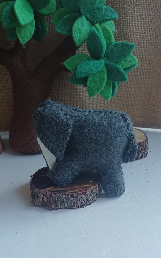 Small felt elephant on a white surface with a blurred background