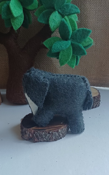 Small felt elephant on a white surface with a blurred background