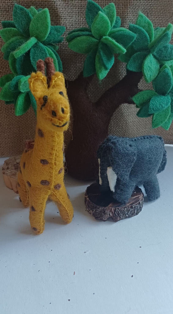 Toy giraffe and elephant with a tree on a white surface