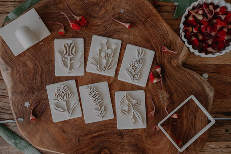 Set of floral stamps on a wooden surface with dried flowers.