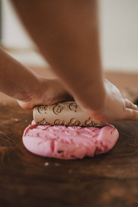 Pink dough with a decorative cookie cutter on a wooden surface.