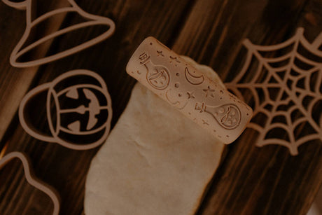 Halloween-themed cookie cutter with carved designs on a wooden surface.