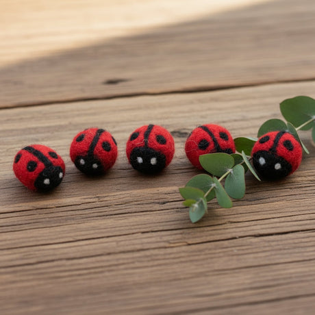 Five mini red felt ladybugs on a wood surface