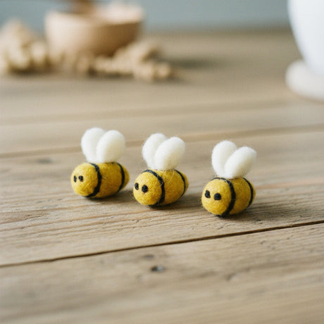 Three yellow felt bees on a wood background