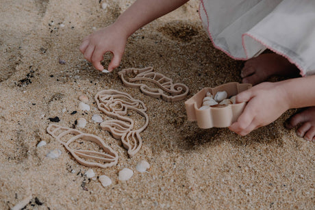 Children playing with sand toys and shells on a sandy beach.