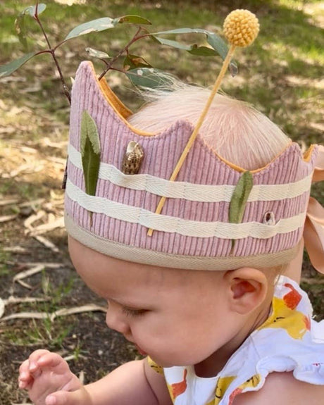 Baby wearing a colorful dress and pink crown outdoors