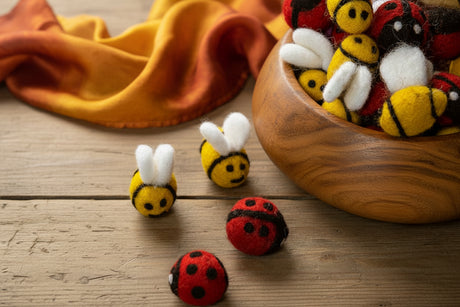 Felted shaped  bees and ladybugs on a wood table in a teak bowl