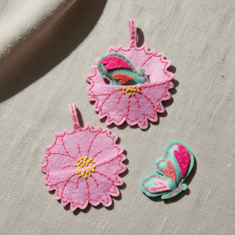 Three pink felt butterflys anf felt flower motif, shown on a plain white background.