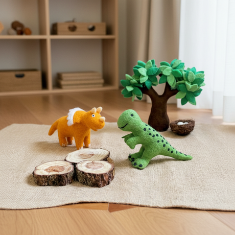 Felt stegasaurus, felt green dinosaur, and decorative tree on a textured surface with a neutral background