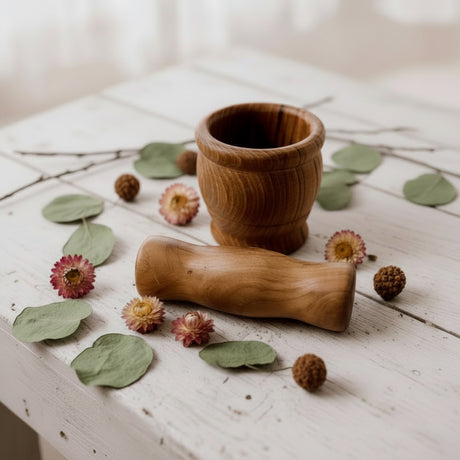 Wooden mortar and pestle on a wooden surface with dried botanicals 