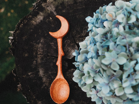 Wooden spoon on a dark surface with blue flowers