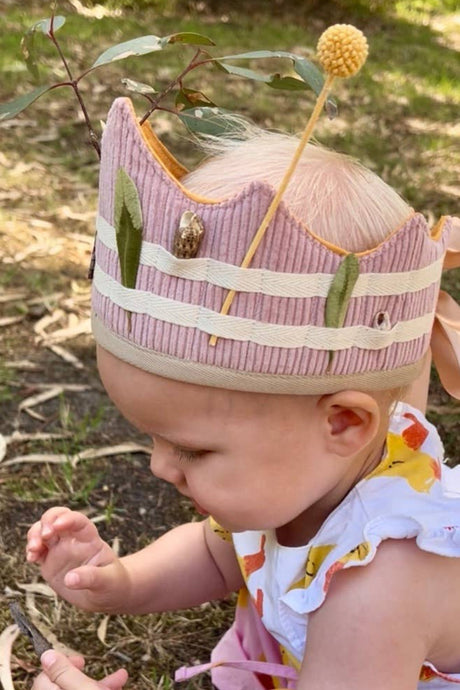 Baby wearing a colorful dress and pink crown outdoors