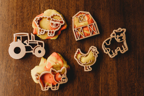 Farm-themed plyadough cutters cutouts on a wooden surface