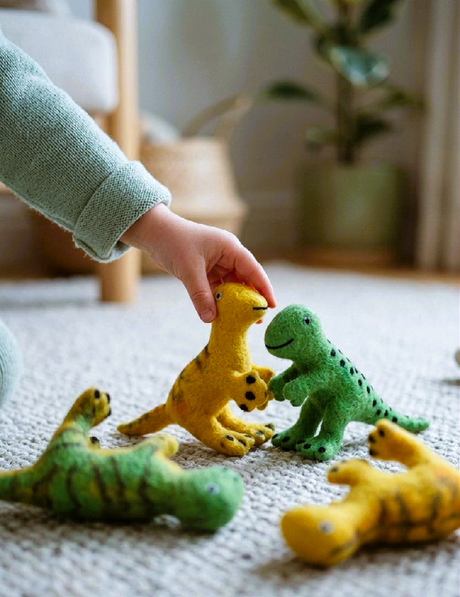 Child's hand reaching towards toy dinosaurs on a textured surface