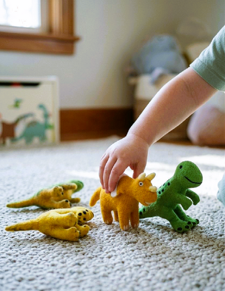 Child playing with toy dinosaurs on a carpeted floor