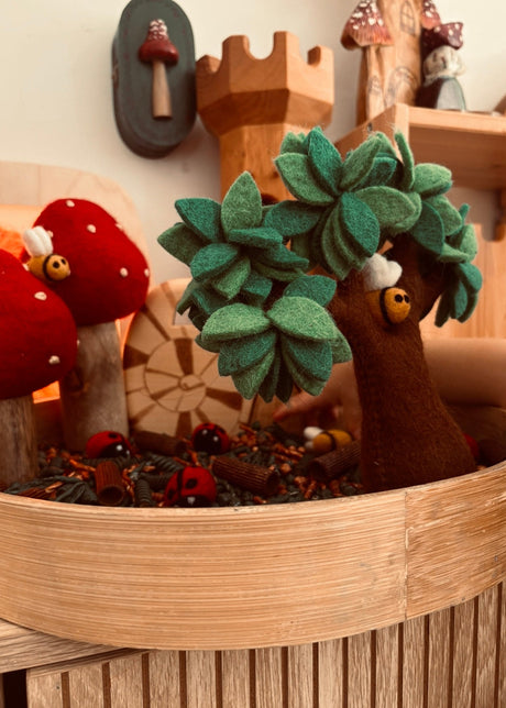 Wooden sensory tray with a felt tree and felt ladbugs on a wooden shelf