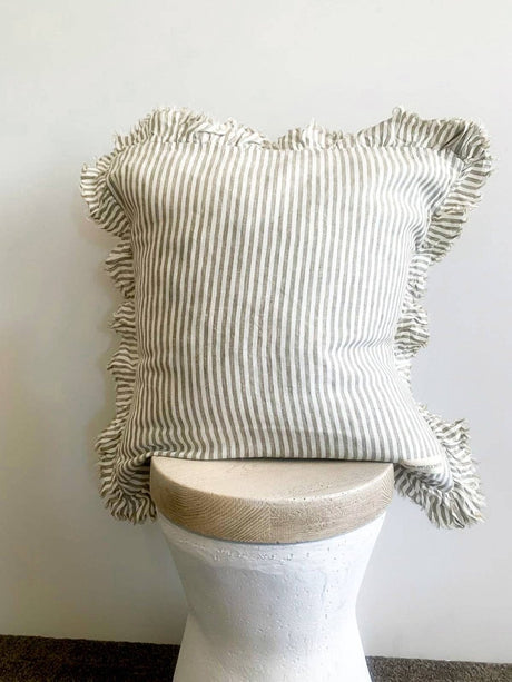 Striped pillow with ruffled edges on a white pedestal against a plain background