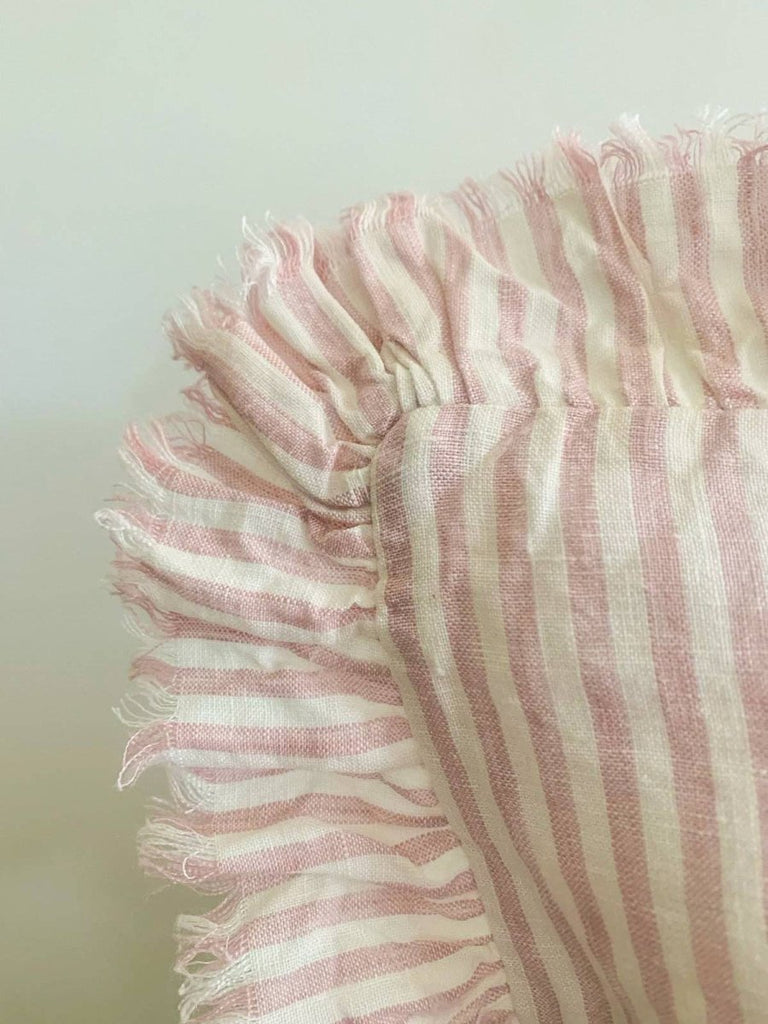 Close-up of a pink and white striped fabric with frayed edges on a light background