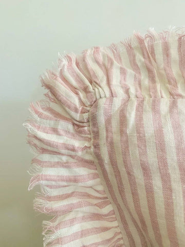 Close-up of a pink and white striped fabric with frayed edges on a light background
