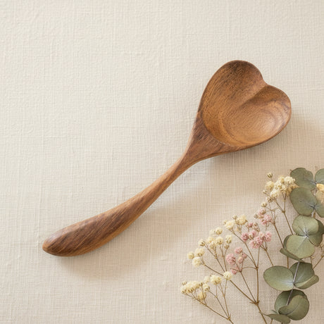 Wooden heart-shaped spoon with two white flowers on a light background