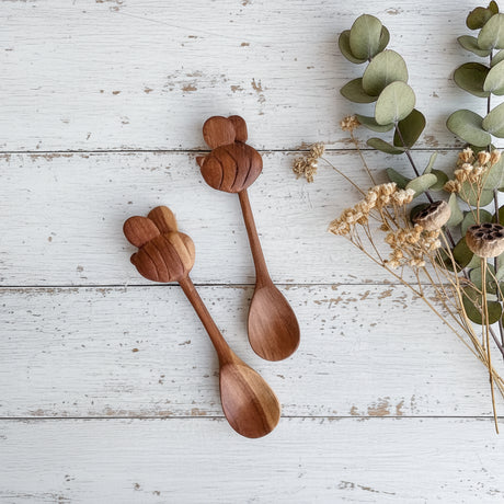 Two wooden spoons with a decorative handle on a white wood surface.