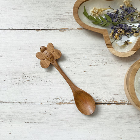 Wooden spoon with bee design on a white wooden surface
