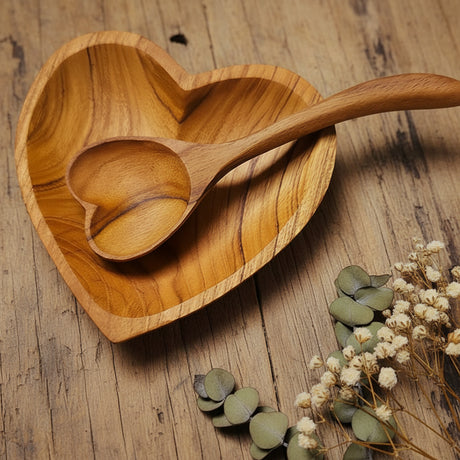 Wooden heart-shaped bowl and spoon on a wood table with dried flowers  